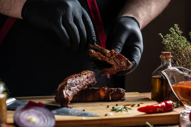 A szakács fekete kesztyűben Grillezett sertésborda a konyhában. Amerikai ételfogalom. gyorskaját. banner, menü, recept, szöveg helye. - Fotó, kép