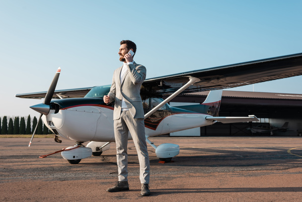 full length of cheerful businessman talking smartphone near helicopter outdoors  - Foto, immagini