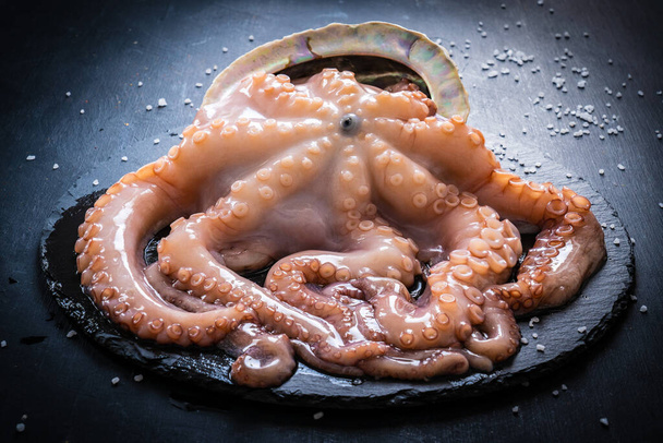 Uncooked octopus and vegetables on black wooden table - Foto, Bild