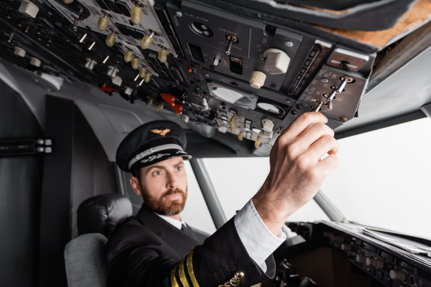 pilot v čepici a uniforma dosahující stropního panelu v simulátoru letounu - Fotografie, Obrázek