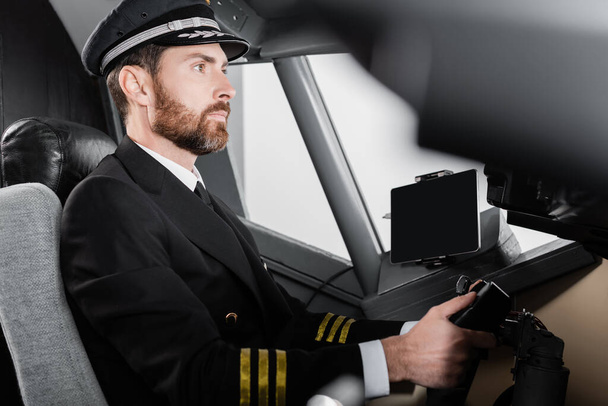 Uçakta boyunduruk kullanan üniformalı sakallı pilotun yan görüntüsü - Fotoğraf, Görsel