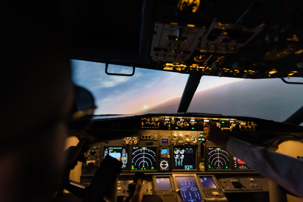 partial view of professionals piloting airplane in evening  - Photo, Image