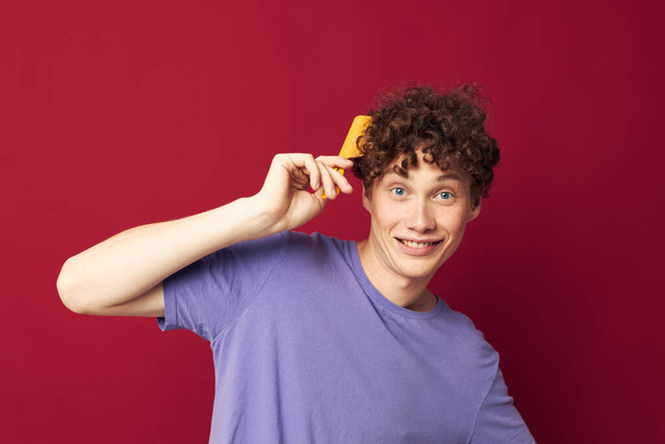 portrait of a young curly man posing hairbrush personal care Youth style - Fotografie, Obrázek