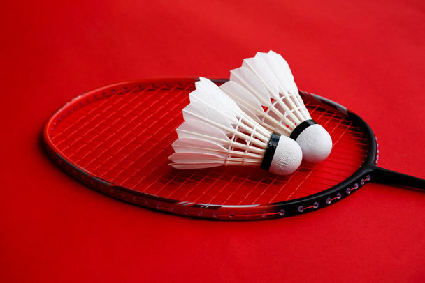 Krém bílý badminton shuttlecock a raketa na červené podlaze v krytém badminton kurtu, kopírovací prostor, měkké a selektivní zaměření na shuttlecocks. - Fotografie, Obrázek