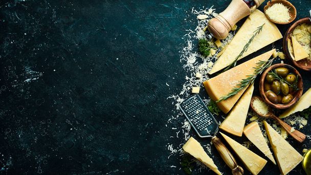 Set of hard cheeses with cheese knives on black stone background. Parmesan. Top view. Free space for your text. - Foto, Bild