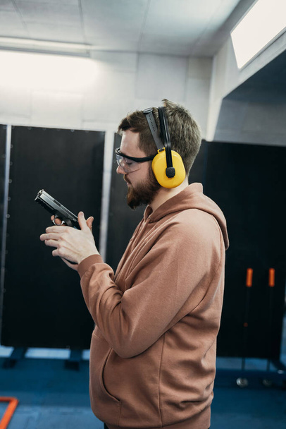 A profile of the face of a serious man who holds a short-barreled weapon in his hands and looks at the target before being fired. shooting range - 写真・画像