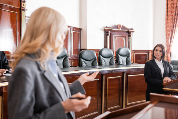 blurred attorney pointing with hand and talking to witness during litigation - 写真・画像