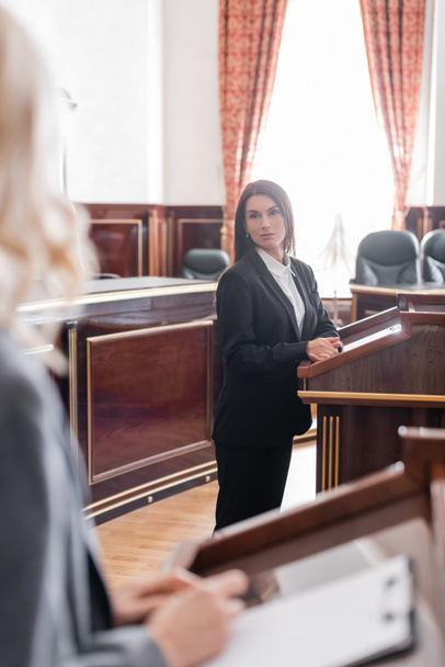 brunette witness looking at blurred prosecutor during litigation in court - Фото, изображение