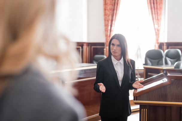 prokurator wskazujący dłońmi podczas rozmowy z niewyraźnym świadkiem na sali sądowej - Zdjęcie, obraz