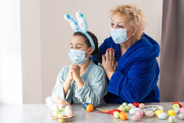 Babcia i wnuczka w domu na kwarantannie z maską medyczną. Koronawirus, choroba, zakażenie, grypa, bandaż chirurgiczny. - Zdjęcie, obraz