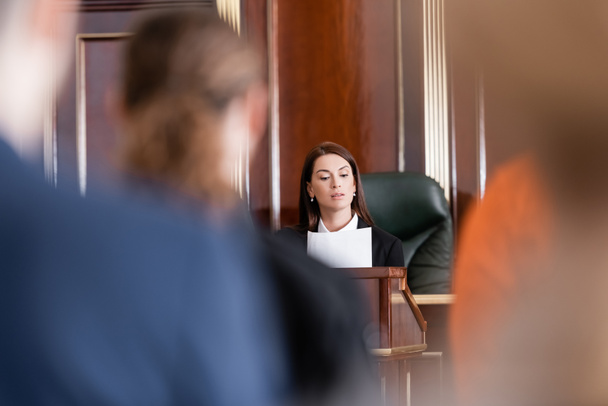 prosecutor reading lawsuit in court near people on blurred foreground - Φωτογραφία, εικόνα