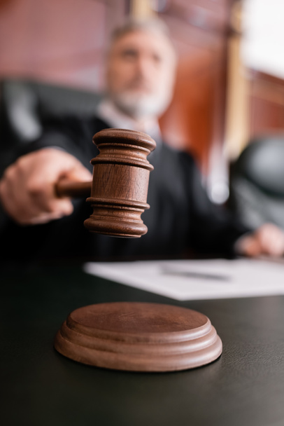 selective focus of wooden gavel in hand of blurred judge in court - 写真・画像