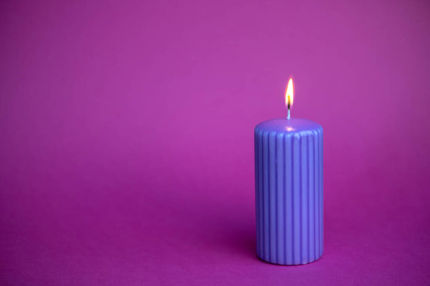 Голубая свеча с оранжевым пламенем на фиолетовом фоне - Фото, изображение