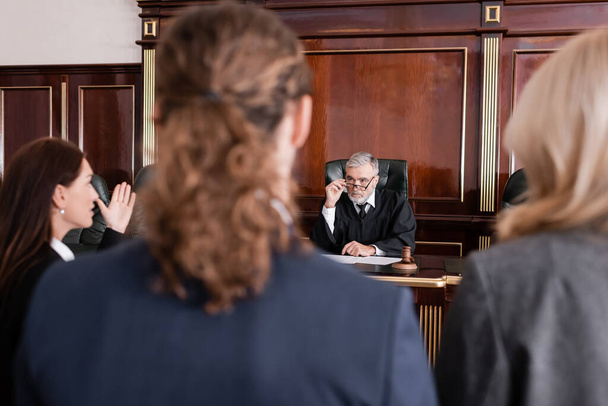 prosecutor pointing with hand while talking to judge near blurred man and advocate - Foto, immagini
