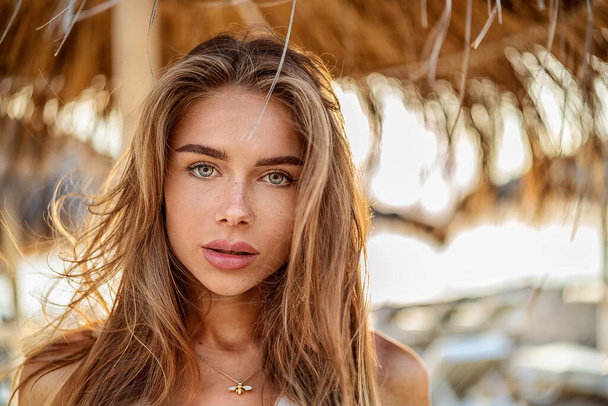 Portrait of natural blonde woman with freckles and long hair. Girl looking at the camera, relaxing on the beach. - Foto, immagini