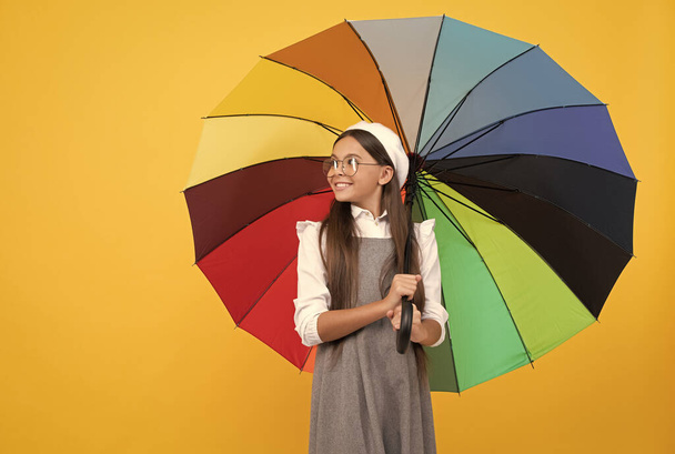 cheerful teen child under colorful parasol. kid in beret with rainbow umbrella. - Photo, Image
