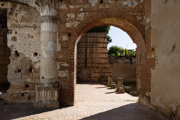 selective focus on ancient ruins of the first American hospital, San Nicols de Bari in Santo Domingo, early 16th century. Arches, columns and walls of red brick and cobblestone - Фото, изображение