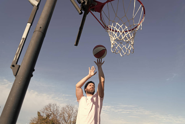 чоловік кидає м'яч у кошик, граючи в баскетбол на літньому спортивному майданчику, спортивна діяльність
 - Фото, зображення