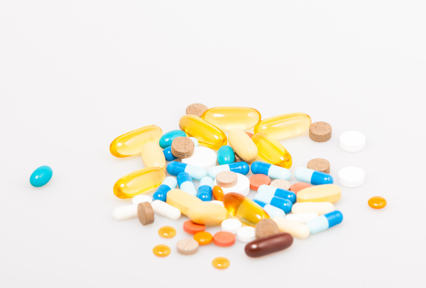 Varie vitamine e integratori alimentari sullo sfondo bianco con dof poco profondo. Il concetto di prevenzione e trattamento delle malattie. Copia spazio - Foto, immagini