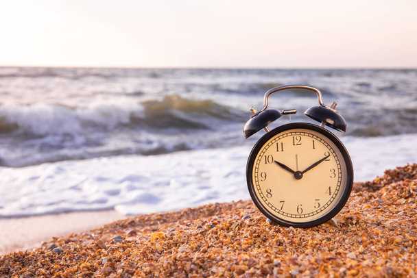 closeup of an alarm clock on the beach adjusting forward one hour at the beginning of the summer time.Morning of a new day.Health concept.alarm clock on the beach sunlight in morning. place for text - Φωτογραφία, εικόνα