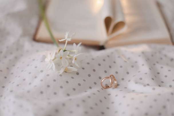 Golden ring and open book with folded sheets in heart shape in bed. Wedding concept, Happy Valentines Day - Foto, imagen