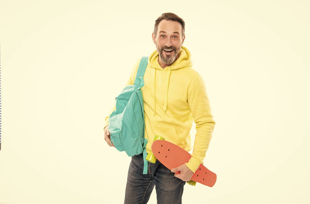 счастливый зрелый мужчина хипстер в капюшоне с рюкзаком и пенни доска изолированы на белом, скейтбординг. - Фото, изображение