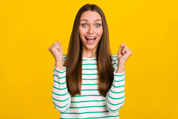 Photo of sweet lucky woman wear striped shirt screaming rising fists isolated yellow color background - Фото, зображення