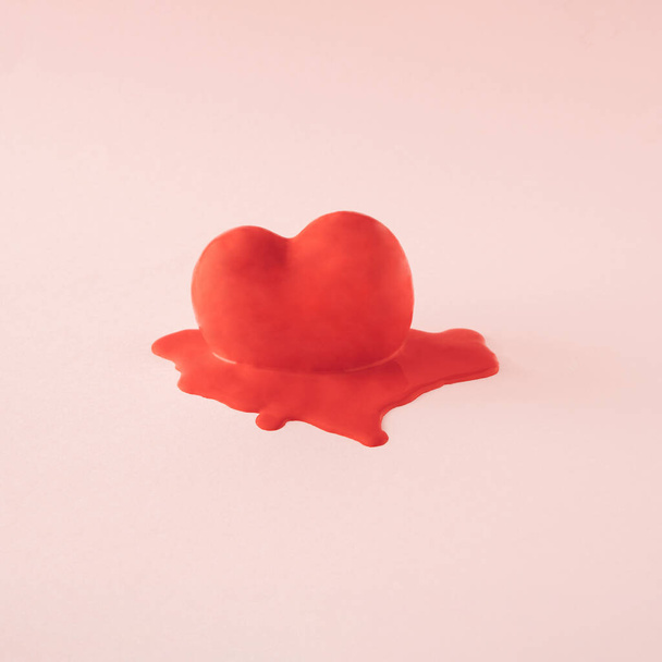 Gesmolten onderste deel van het rode hart dat staat in zijn rode kleur. Minimaal concept van Valentijnsdag op een beige achtergrond. Een symbool van liefde - Foto, afbeelding