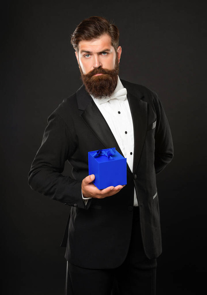 man in tuxedo bow tie formalwear on black background with box. valentines day - Фото, изображение