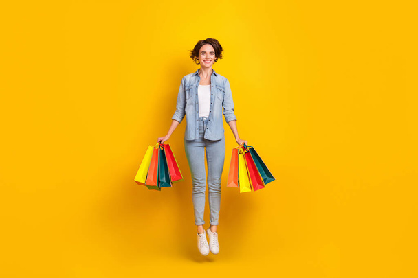 Full length photo of young lady jump up shop boutique new collection isolated over yellow color background - Foto, immagini