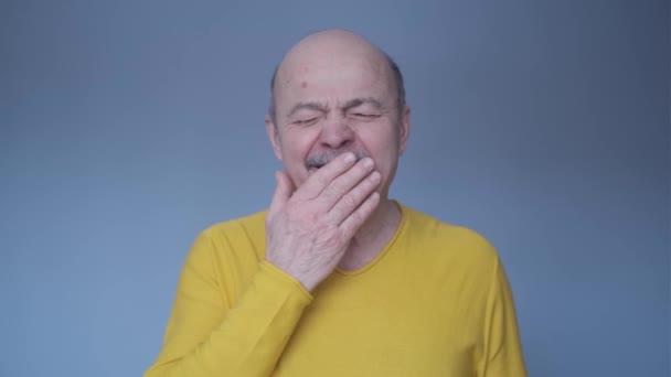 Hombre mayor aburrido bostezando cansado cubriendo la boca con la mano - Imágenes, Vídeo