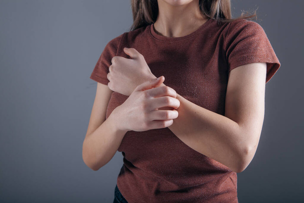young woman has wrist pain on gray background - Fotoğraf, Görsel