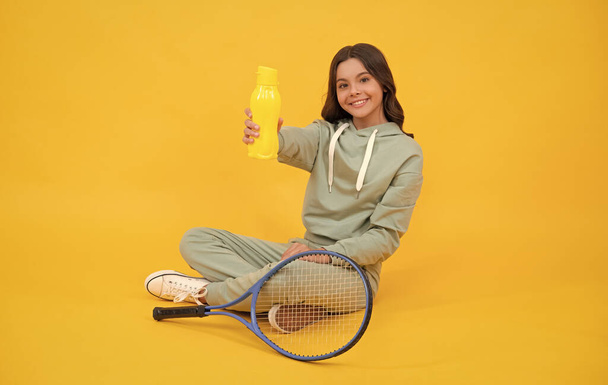 Kind mit Tennisschläger. Teenie-Mädchen trinken nach dem Sport Wasser. Badmintonspieler entspannen. - Foto, Bild