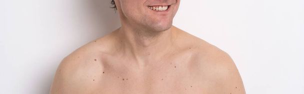Men beauty skin care ads concept. Man with smile and bare shoulders looking sideways of camera isolated on white background. Men cosmetology concept. Age spots and man skin care concept - 写真・画像