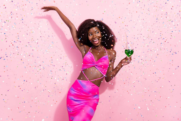 ピンクのパステルカラーの背景に孤立した楽しいお祝いのダンスを持っている魅力的な屈託のない陽気な波状の髪の女の子の肖像 - 写真・画像
