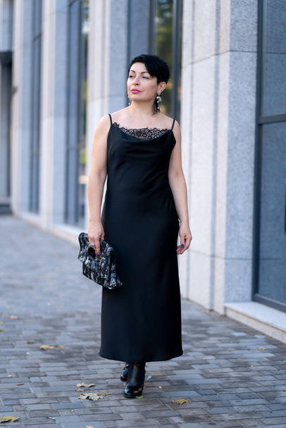 Elegant woman in a stylish black dress posing on a city street. - Photo, Image