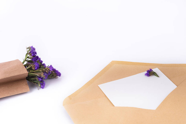 Mavi, kahverengi kesekağıdında kurumuş çiçekler ve beyaz arka planda temiz kağıtlarla dolu posta zarfları. Üst görünüm, boşluğu kopyala. Bahar konseptini izole et - Fotoğraf, Görsel