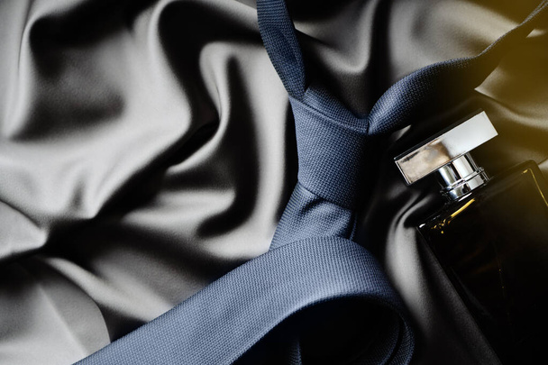 Elegant man accessories: tie and perfume bottle on the satin textile. Background with copy space. - Foto, Imagem