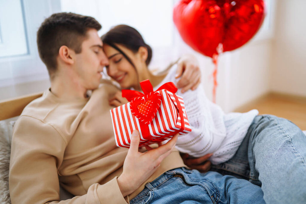 Valentine's Day concept. Lovers give each other gifts. Young couple at home celebrating Valentine's Day. - Fotoğraf, Görsel