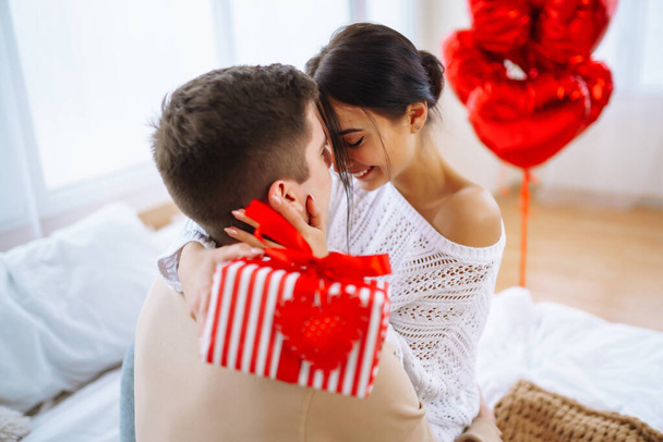 Valentine's Day concept. Lovers give each other gifts. Young couple at home celebrating Valentine's Day. - Foto, Imagem