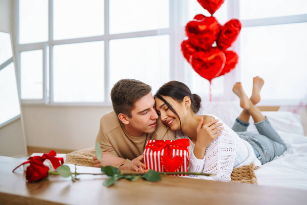 Concepto del Día de San Valentín. Los amantes se dan regalos. Pareja joven en casa celebrando el Día de San Valentín. - Foto, Imagen