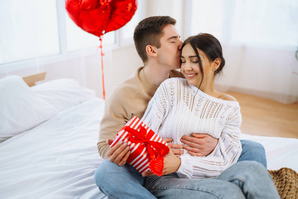 Valentine's Day concept. Lovers give each other gifts. Young couple at home celebrating Valentine's Day. - Zdjęcie, obraz
