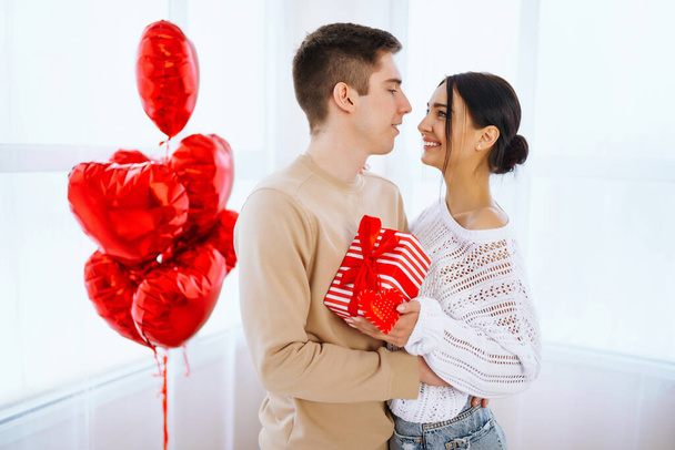 Valentine's Day concept. Lovers give each other gifts. Young couple at home celebrating Valentine's Day. - Fotografie, Obrázek
