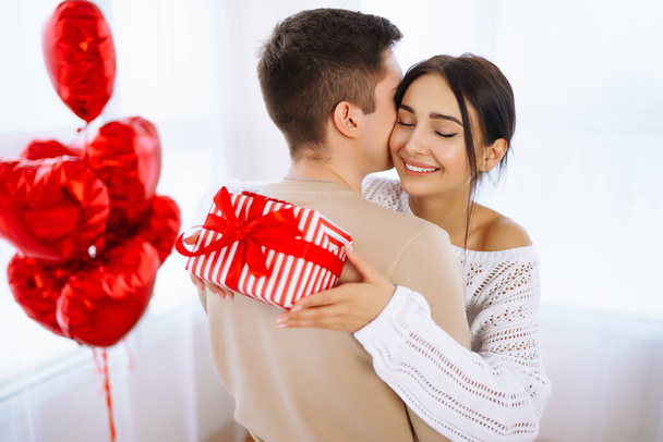 Valentine's Day concept. Lovers give each other gifts. Young couple at home celebrating Valentine's Day. - Fotó, kép