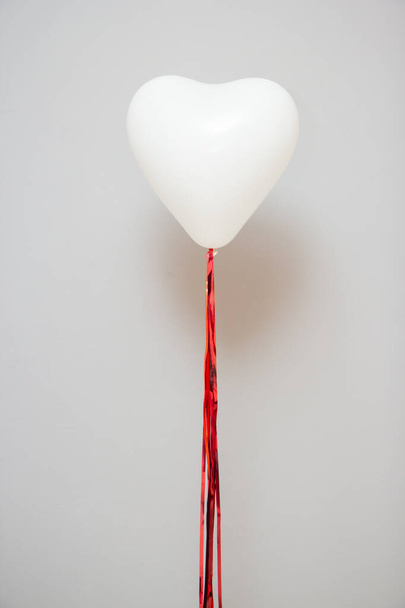 Witte ballon in de vorm van een hart met een rode slinger, hartballon voor Valentijnsdag - Foto, afbeelding
