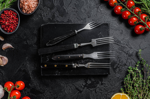 Rustic Cutting Board and meat fork on Dark wooden board. Black background. Top view. Copy space - Foto, Imagem