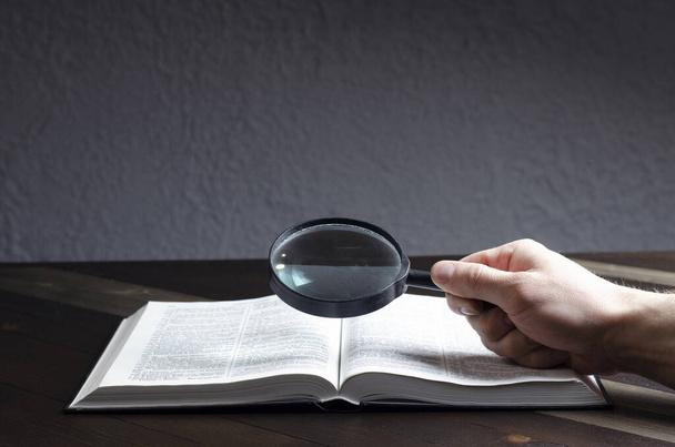 Open Bible. Magnifier in hand. On the table. Holy Bible, Scripture. Magnifier - 写真・画像
