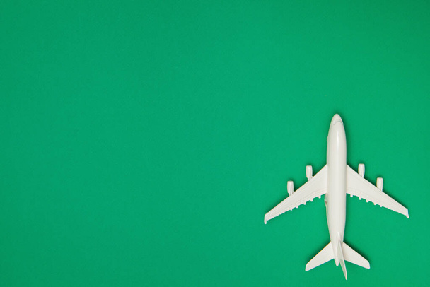 Airplane model. White plane on green background. Travel vacation concept. Summer background. Flat lay, top view, copy space. - Foto, Imagen