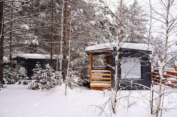 Modular house made of dark metal and light wood in winter forest. a house that takes into account everything you need for a comfortable life outside the city. High quality photo - Fotó, kép