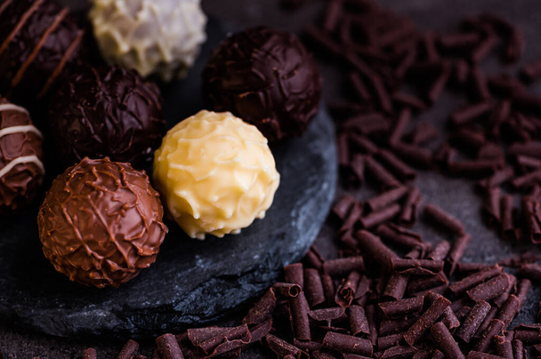 truffes au chocolat sur une petite ardoise sur fond sombre à côté sont couchés flocons de chocolat - Photo, image